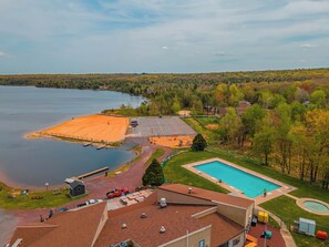 A residential area with a swimming pool, a large open field, and a lake.
