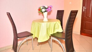 Un coin repas avec une table ronde, quatre chaises et un vase de fleurs posé sur la table.
