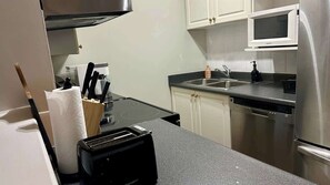 A compact kitchen with a microwave, dishwasher, and a toaster. - Urban Downtown Condo with Panoramic Views (Calgary)