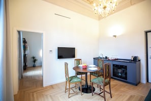 A dining area with a round table, chairs, a flat-screen TV, and a kitchen area with a stove and cabinets. - Luxury Boutique Apartment 3 in Palermo City Center, near the Central Station (Palermo)