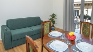 A dining area with a wooden table set for four, a green sofa, and a chandelier. - Luxury Boutique Apartment 3 in Palermo City Center, near the Central Station (Palermo)