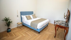 A bedroom with a bed, a small table, a chair, a potted plant, and a wall-mounted lamp. - Luxury Boutique Apartment 3 in Palermo City Center, near the Central Station (Palermo)