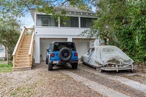 Ein zweistöckiges Haus mit Garage, einem überdachten Auto und einer Holztreppe, die zur Garage führt.