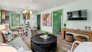 Uma sala de estar acolhedora com uma mesa redonda preta, um sofá e um espaço de refeições com uma porta verde.
