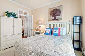 Ein Schlafzimmer mit einem Bett, einem Schrank, einem Nachttisch, einer Lampe, einem Wandbild und einem Regal.