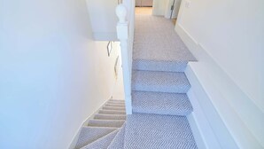 A staircase with a patterned carpet, white walls, and a white balustrade. - 3 Bed Foyle View House In Derry City With Parking (Derry/Londonderry)
