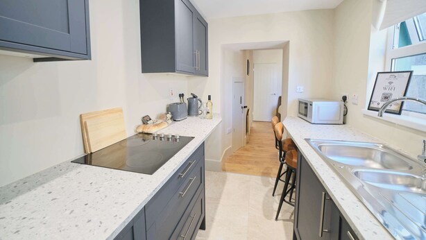 A modern kitchen with a central island, a microwave, and a sink. - 3 Bed Foyle View House In Derry City With Parking (Derry/Londonderry)