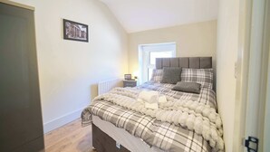 A bedroom with a bed, a nightstand, a window, and a door. - 3 Bed Foyle View House In Derry City With Parking (Derry/Londonderry)