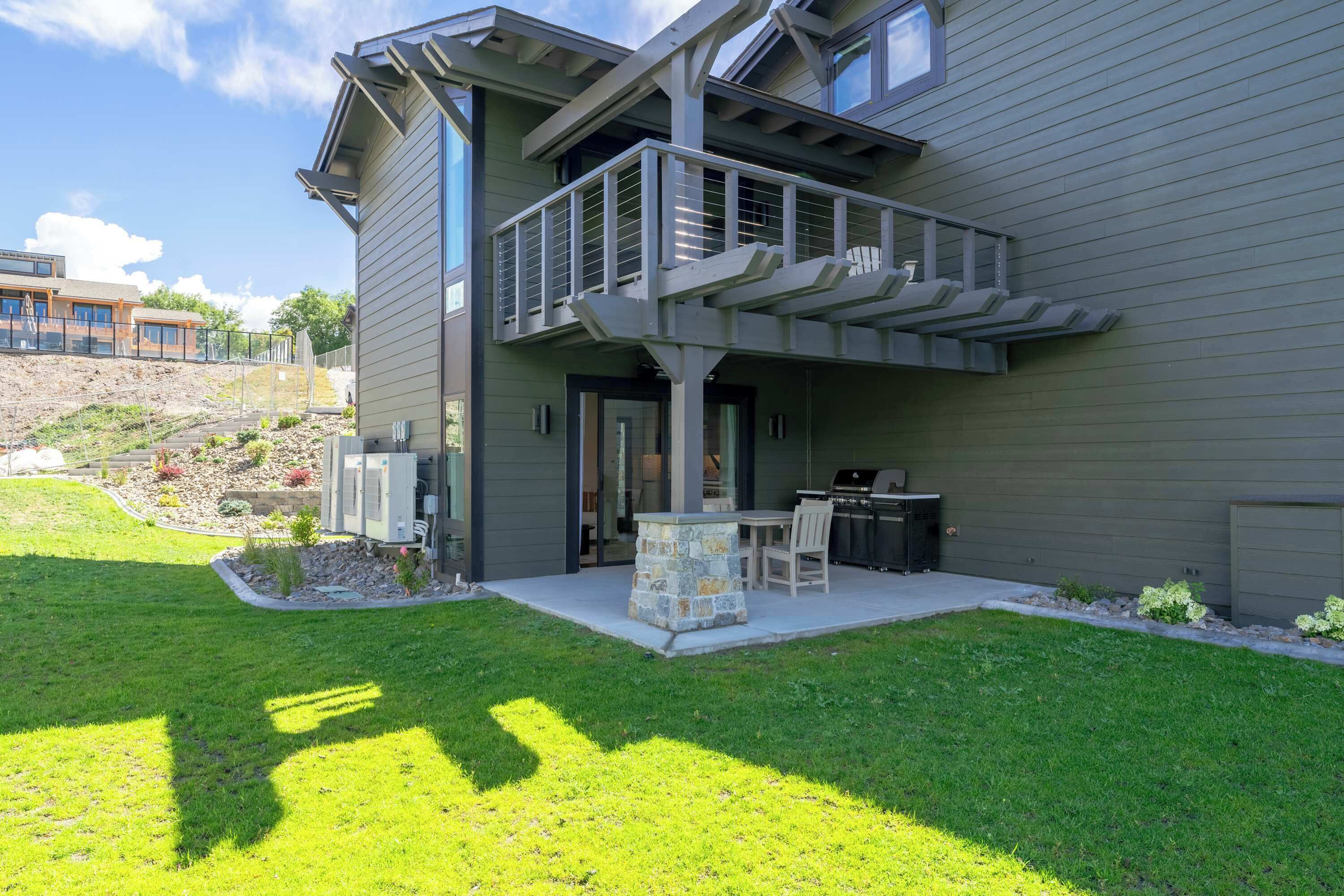 Een modern herenhuis met twee verdiepingen, een balkon, terrasmeubilair en een stenen openhaard.