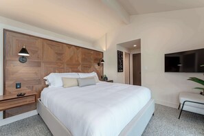A modern bedroom with a large bed, wooden headboard, bedside lamps, a flat-screen TV, and a small seating area. - High-end Lakefront Condo B6 Wapato Point Chelan (Manson)