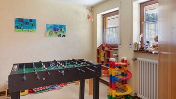 Una habitación con mesa de fútbol, dibujos infantiles en la pared y ventana con vistas.