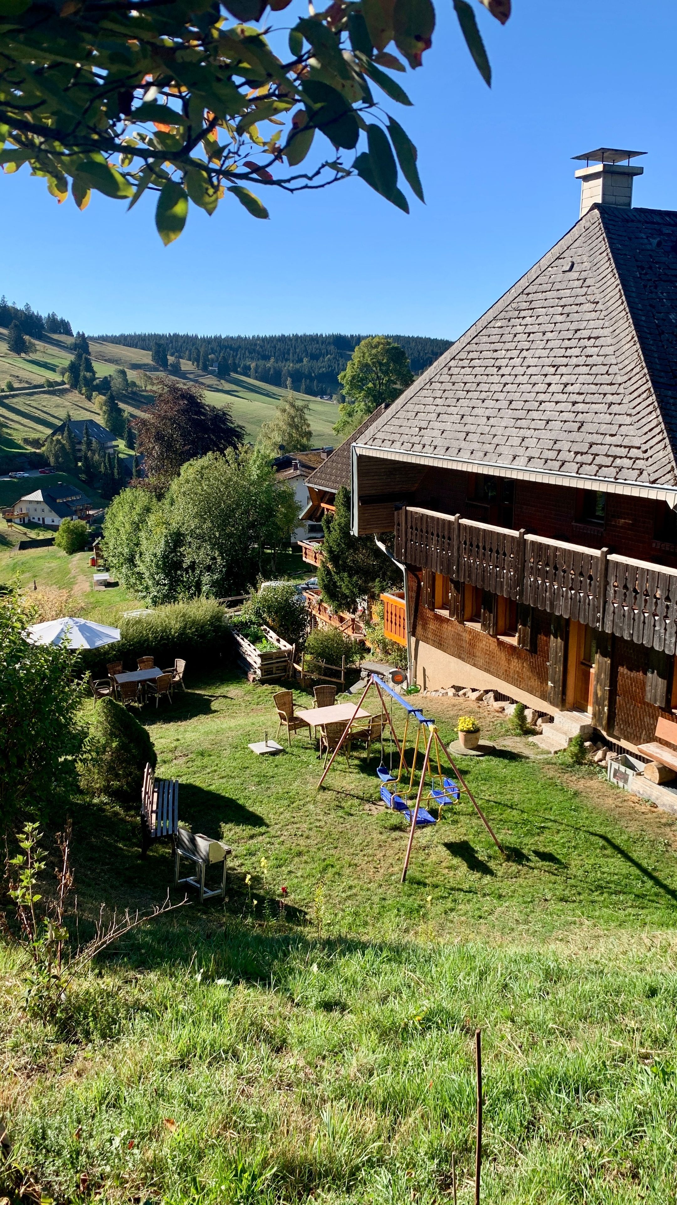 A traditional house with a sloped roof, a wooden fence, and a swing set in the yard.