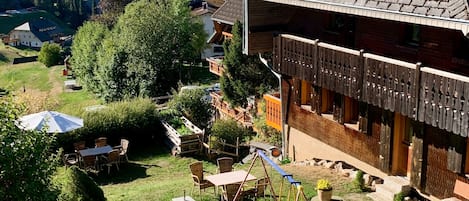 A traditional house with a sloped roof, a wooden fence, and a swing set in the yard.