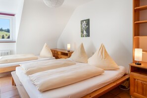 Ein Schlafzimmer mit zwei Betten, einer Holzkommode, einem Nachttisch mit Lampe und einem Bild an der Wand.