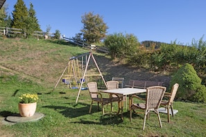 Eine Terrassenfläche mit Schaukel, Korbmöbeln, einem Tisch und einem Blumentopf.