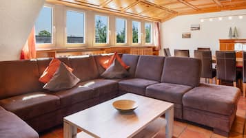 Een gezellige zithoek met een hoekbank, een houten salontafel en een eethoek met stoelen en een tafel.