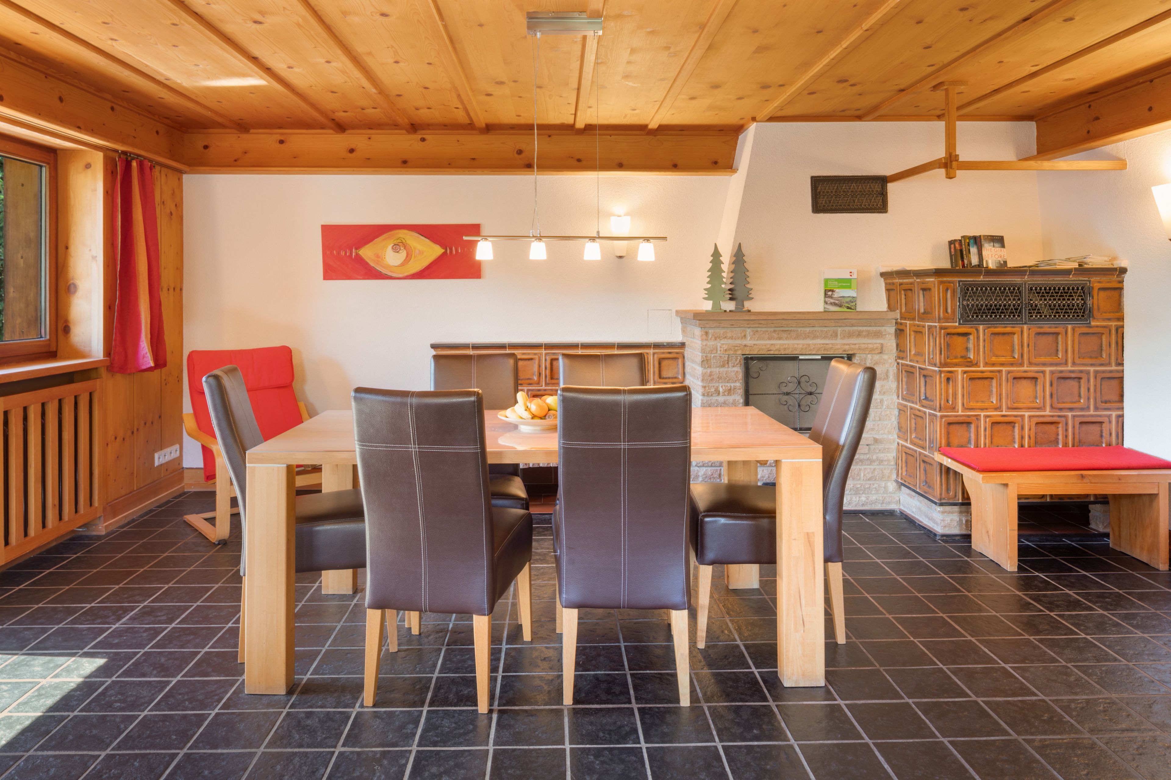 Un coin repas avec une table et des chaises en bois, une cheminée et une bibliothèque.