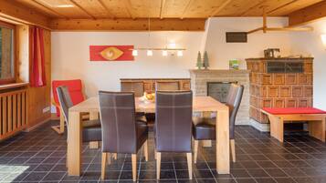 Un coin repas avec une table et des chaises en bois, une cheminée et une bibliothèque.
