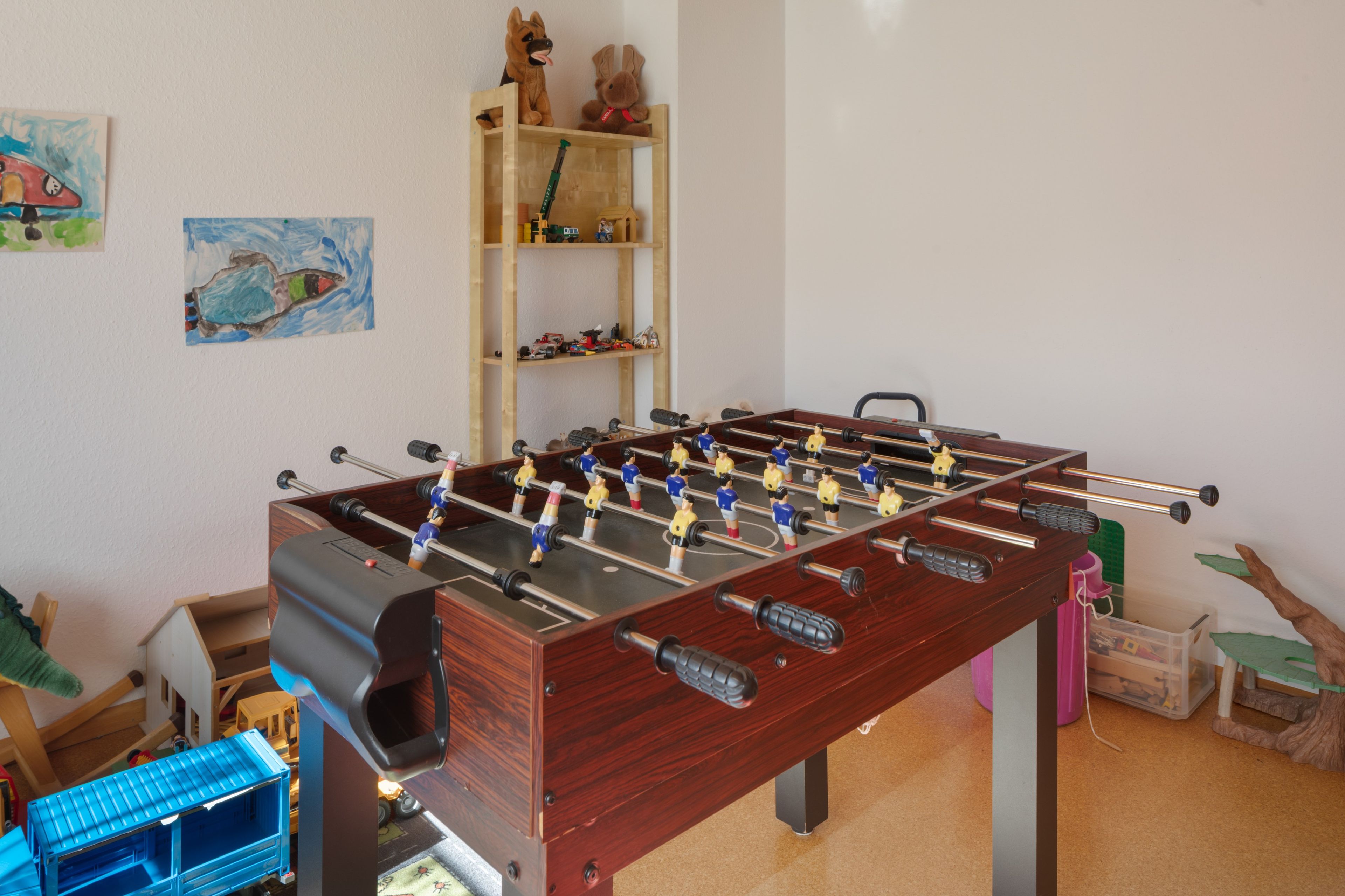 Een tafelvoetbaltafel in een kamer met een houten plank en speelgoed.