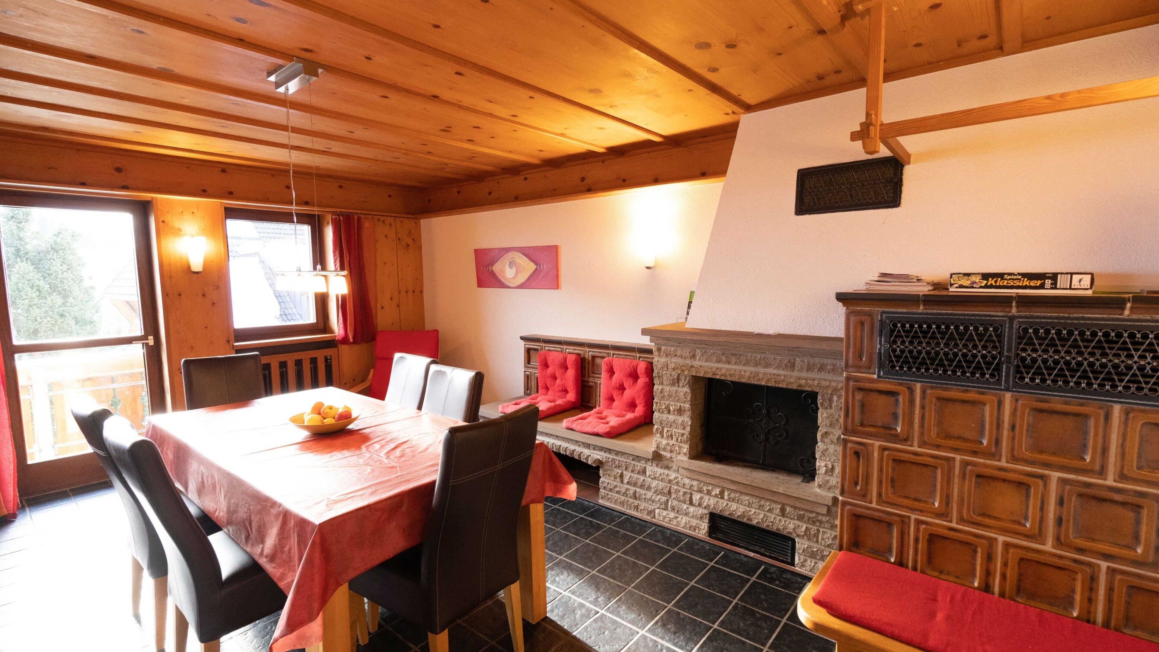Ein Essbereich mit einem für vier Personen gedeckten Tisch, einem Kamin mit Steinverkleidung und einem mit Vorhängen drapierten Fenster.