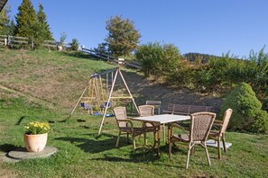 A patio area with a swing set, wicker chairs, a table, and a potted plant. - Gästehaus Bühlhof Todtnauberg Apartment 4 (Todtnau)