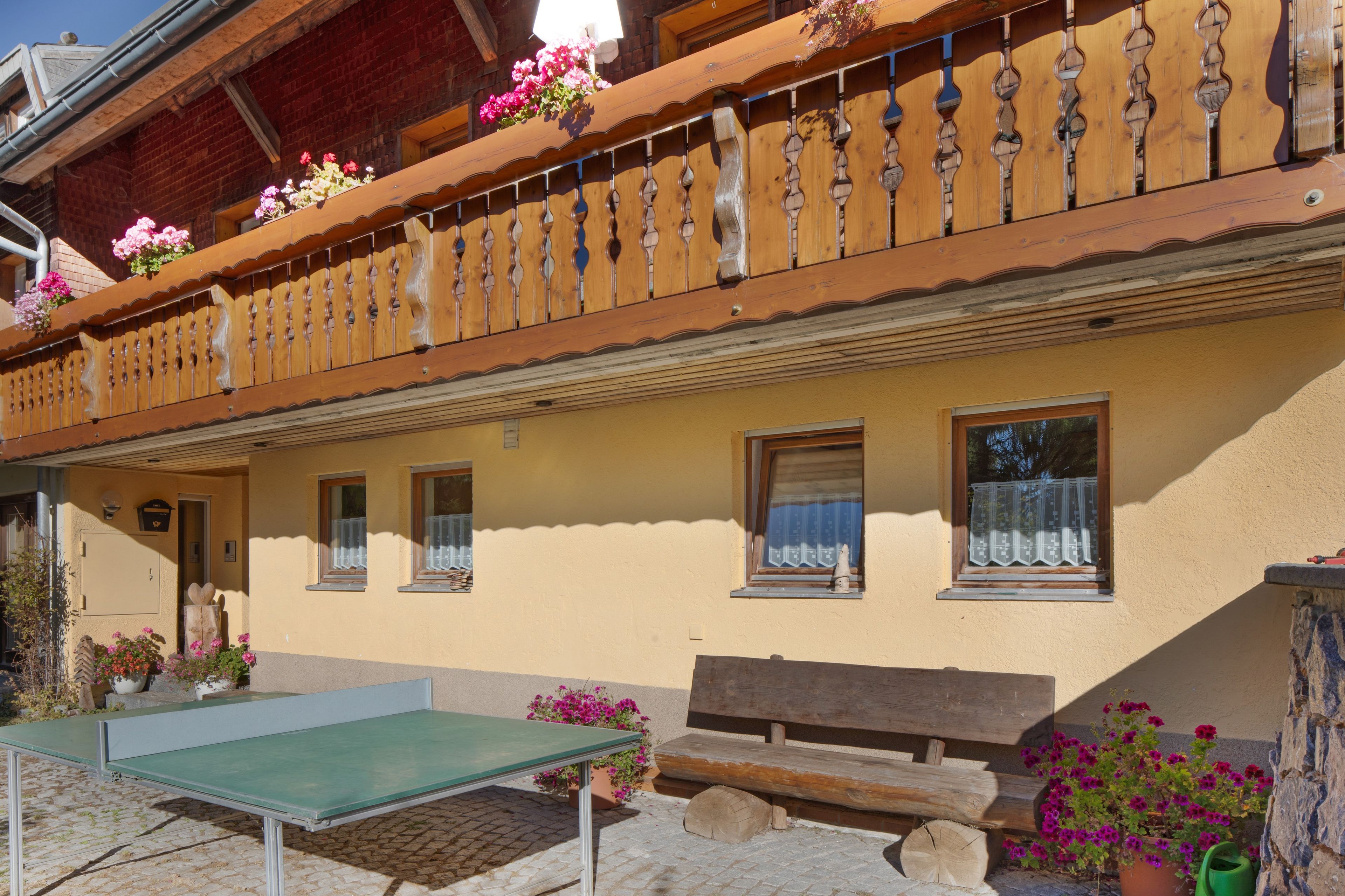 Ein Gebäude mit Balkon, Fenstern und Außenbestuhlung.