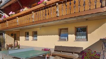 Ein Gebäude mit Balkon, Fenstern und Außenbestuhlung.