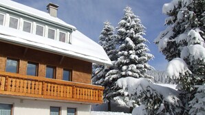 A two-story building with a balcony, surrounded by snow-covered trees and a clear sky. - Apartment 4 at Gästehaus Bühlhof in Todtnauberg (Todtnau)