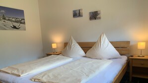 A double bed with two pillows, a wooden headboard, and two bedside tables with lamps. - Apartment 4 at Gästehaus Bühlhof in Todtnauberg (Todtnau)
