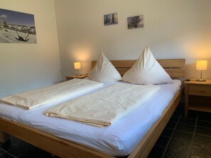 A double bed with two pillows, a wooden headboard, and two bedside tables with lamps. - Apartment 4 at Gästehaus Bühlhof in Todtnauberg (Todtnau)