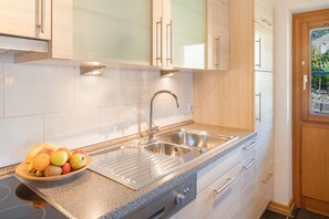 Eine moderne Küche mit Spüle aus Edelstahl, einer Arbeitsplatte aus Granit und Holzschränken.