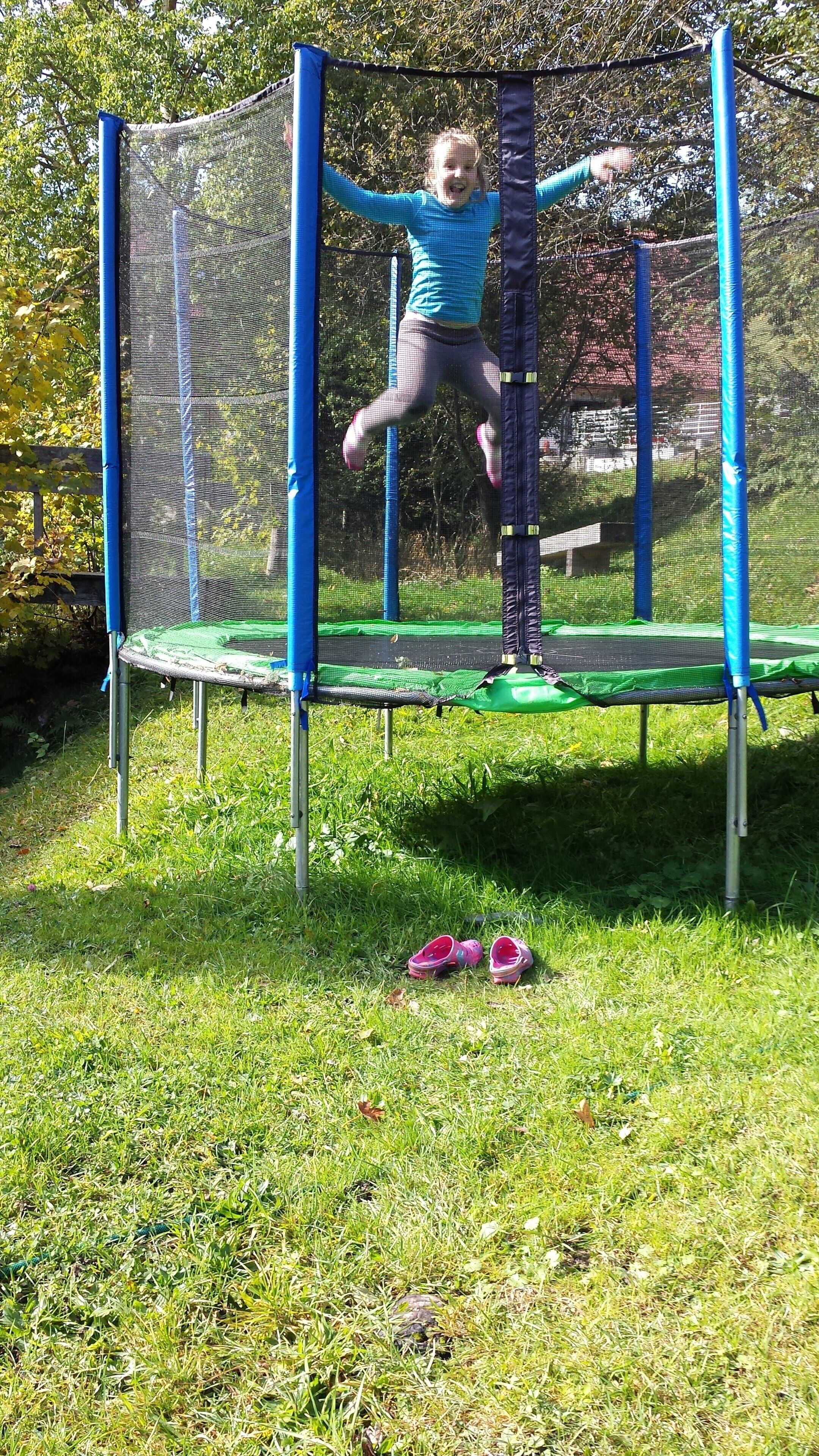 Een kind springt op een trampoline met veiligheidsnet.
