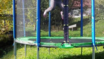 Een kind springt op een trampoline met veiligheidsnet.