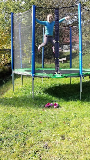 A child jumping on a trampoline with safety netting. - Apartment 4 at Gästehaus Bühlhof in Todtnauberg (Todtnau)