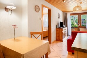 A room with a dining table, a chair, a television, and a view of the outdoors. - Bühlhof Todtnauberg Apartment 1 (Todtnau)