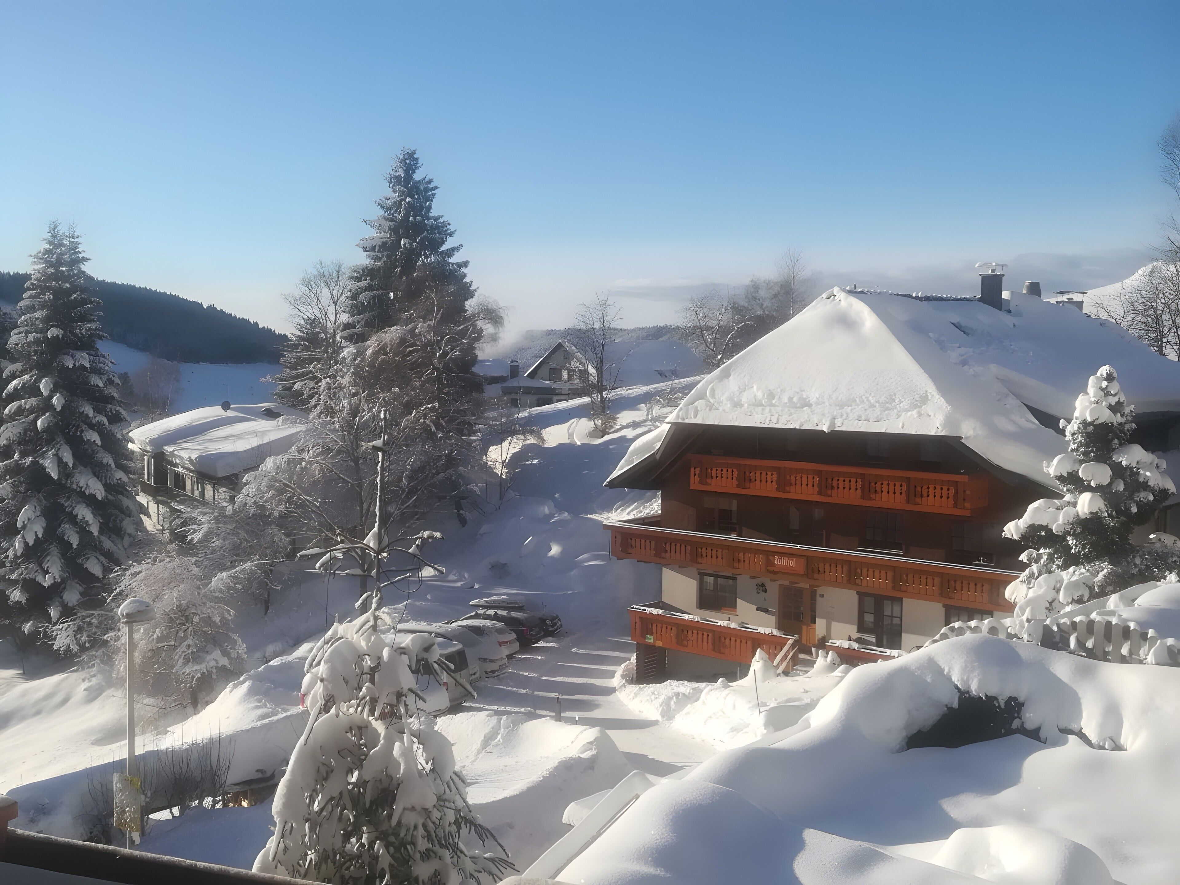 Een besneeuwde lodge met een groot balkon en een helder uitzicht op het besneeuwde landschap.