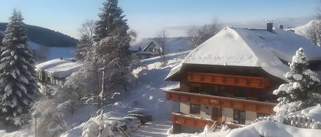 A snow-covered lodge with a prominent balcony and a clear view of the surrounding snowy landscape.