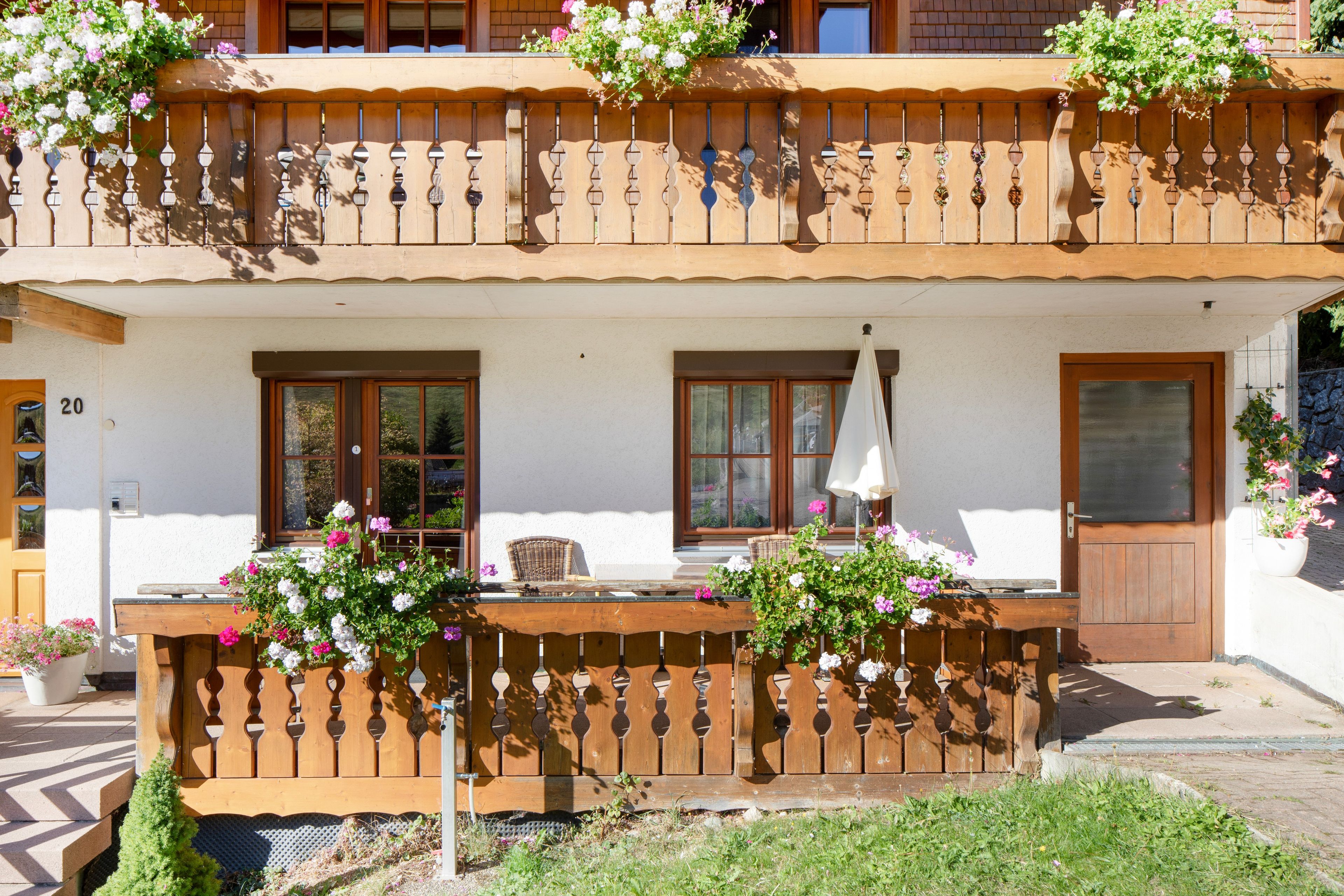 Een gebouw met twee verdiepingen, een balkon, houten leuningen en bloempotten.