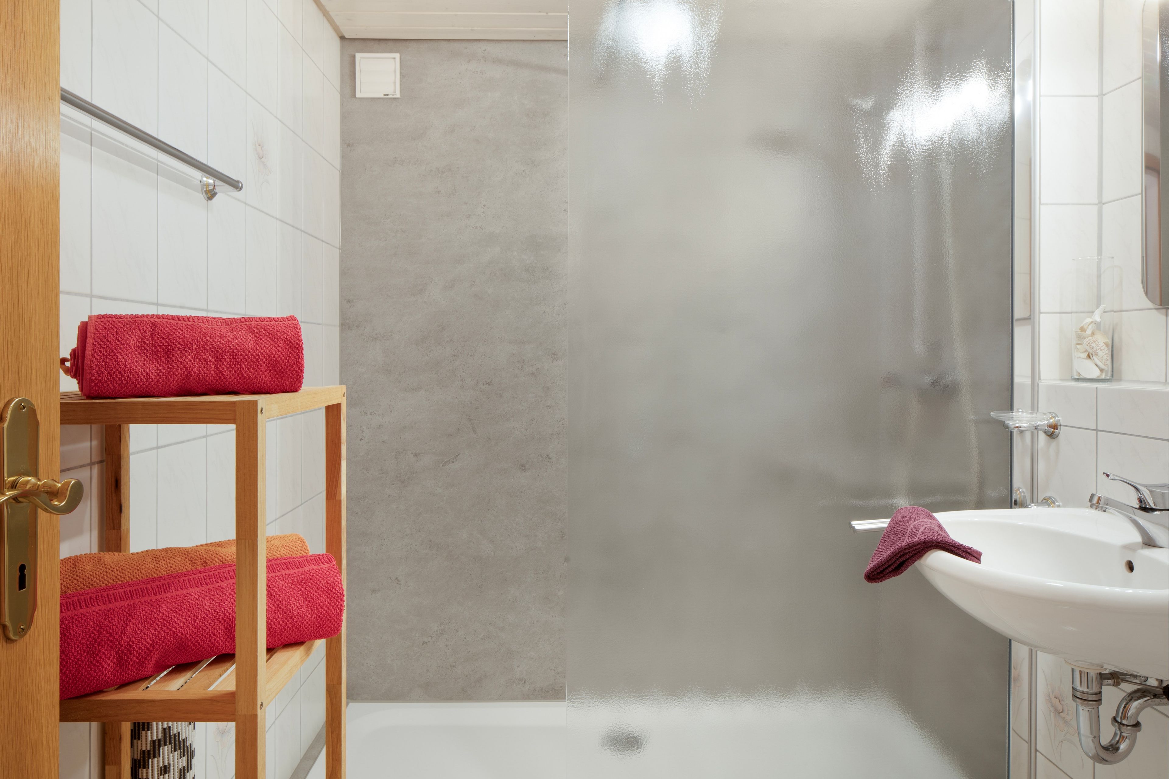 A bathroom with a shower, a sink, and a towel rack.