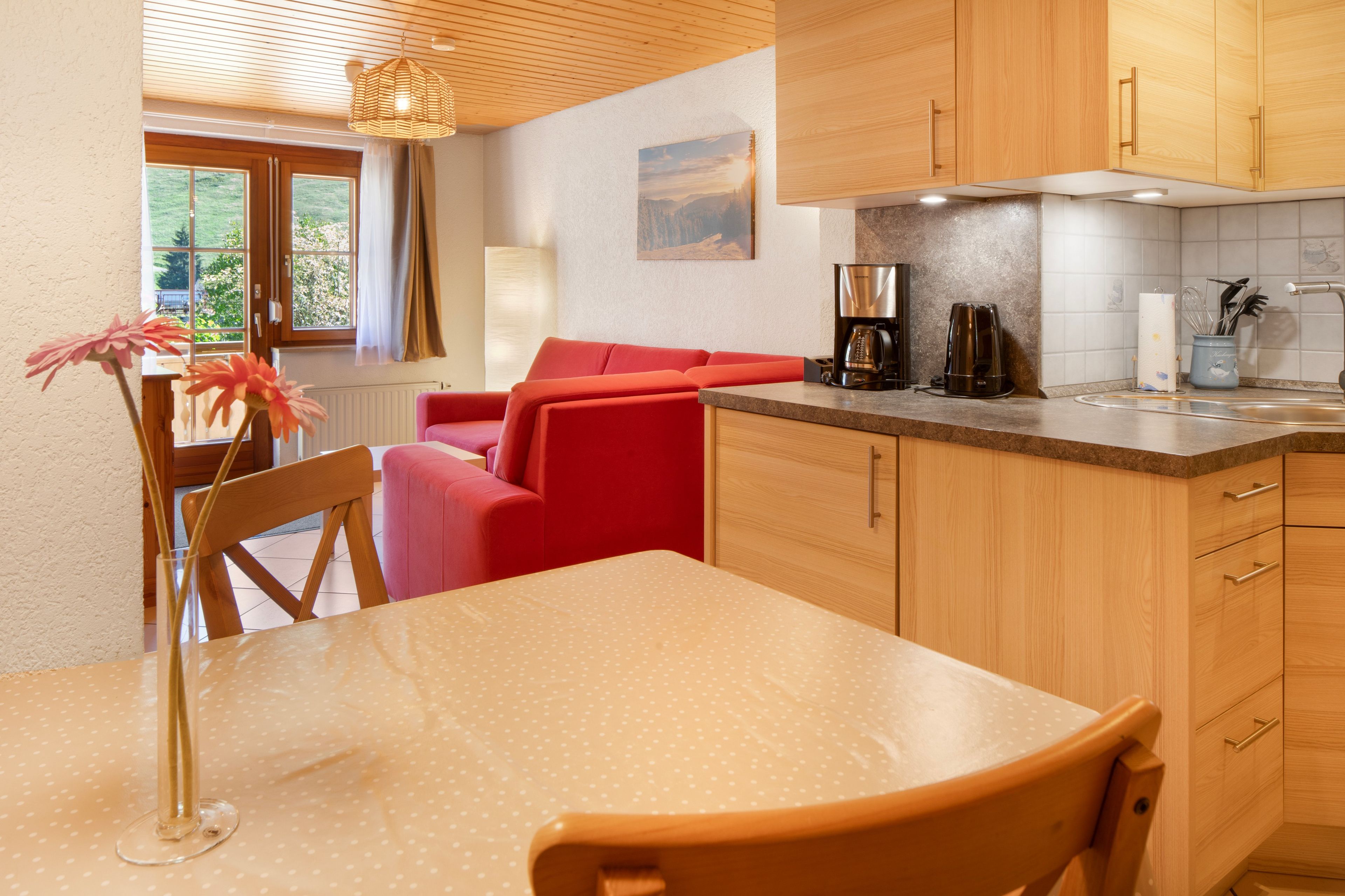 Una cocina moderna con armarios de madera, una mesa de comedor y un sofá rojo.