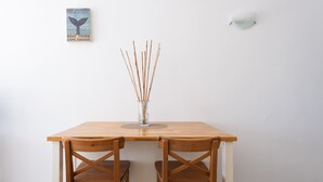 A wooden table with two chairs, a clear vase with sticks, a wall-mounted light, and a poster on the wall. - Apartment in Las Palmas by Las Canteras Beach (Las Palmas de Gran Canaria)