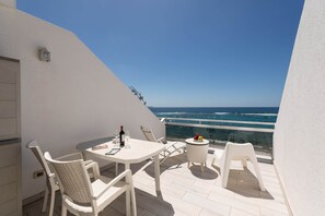 A balcony with a table and chairs, a bottle of wine, and a fruit bowl. - Apartment in Las Palmas by Las Canteras Beach (Las Palmas de Gran Canaria)