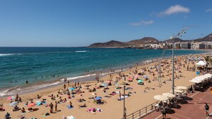A crowded beach with people sunbathing and swimming, a clear sky, and buildings in the background. - Apartment in Las Palmas by Las Canteras Beach (Las Palmas de Gran Canaria)