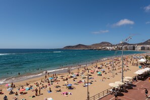 A crowded beach with people sunbathing and swimming, a clear sky, and buildings in the background. - Apartment in Las Palmas by Las Canteras Beach (Las Palmas de Gran Canaria)