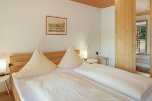 A neatly made bed with white linens and pillows, a bedside table with a lamp, and a framed picture on the wall. - Bühlhof Todtnauberg Apartment 3 (Todtnau)