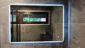 A bathroom with a built-in television screen, a towel rack, and a shower area. - Apricola By ca-sa check (Aprica)