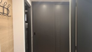 Une porte fermée avec une poignée, un mur en bois à texture marquée sur la gauche et un mur uni sur la droite.