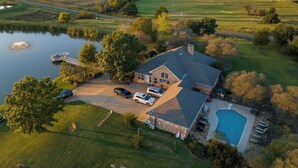 A large house with a swimming pool, a dock, and a driveway with cars parked. - 11 Luxury Acres Retreat, Pool, Fishing, Sleeps 14-24 (Mabank)