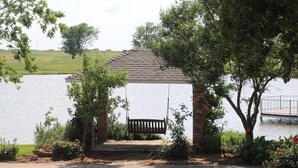 A gazebo with a swing, surrounded by trees and a lake view. - 11 Luxury Acres Retreat, Pool, Fishing, Sleeps 14-24 (Mabank)