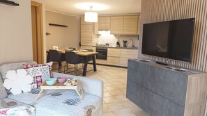 Ein Wohnzimmer mit einer Couch, einem Couchtisch und einem Fernseher auf einem Schrank.